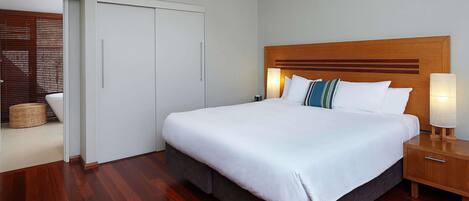 Una habitación de hotel con una cama grande, cabecero de madera, lámparas de noche y un armario.