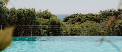 Une piscine offrant une vue sur l’océan et entourée d’une végétation luxuriante.