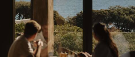 A dining area with a view of the sea, featuring a table with chairs and a glass partition.