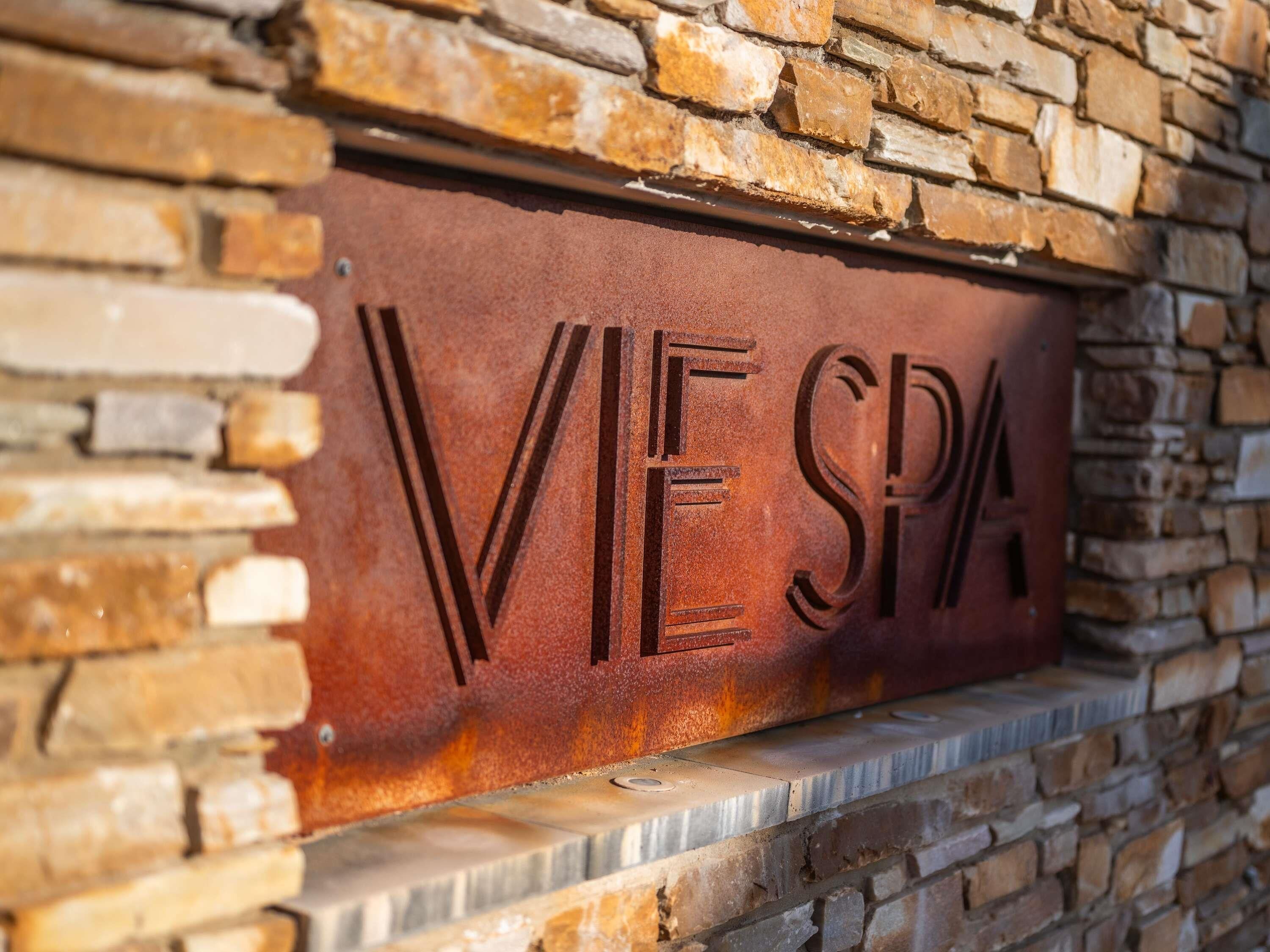 Una placa de metal con el grabado 'VIE SPA', fijada a una pared de piedra.