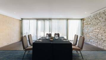 Un salón de conferencias con una larga mesa, sillas y una pared de piedra.
