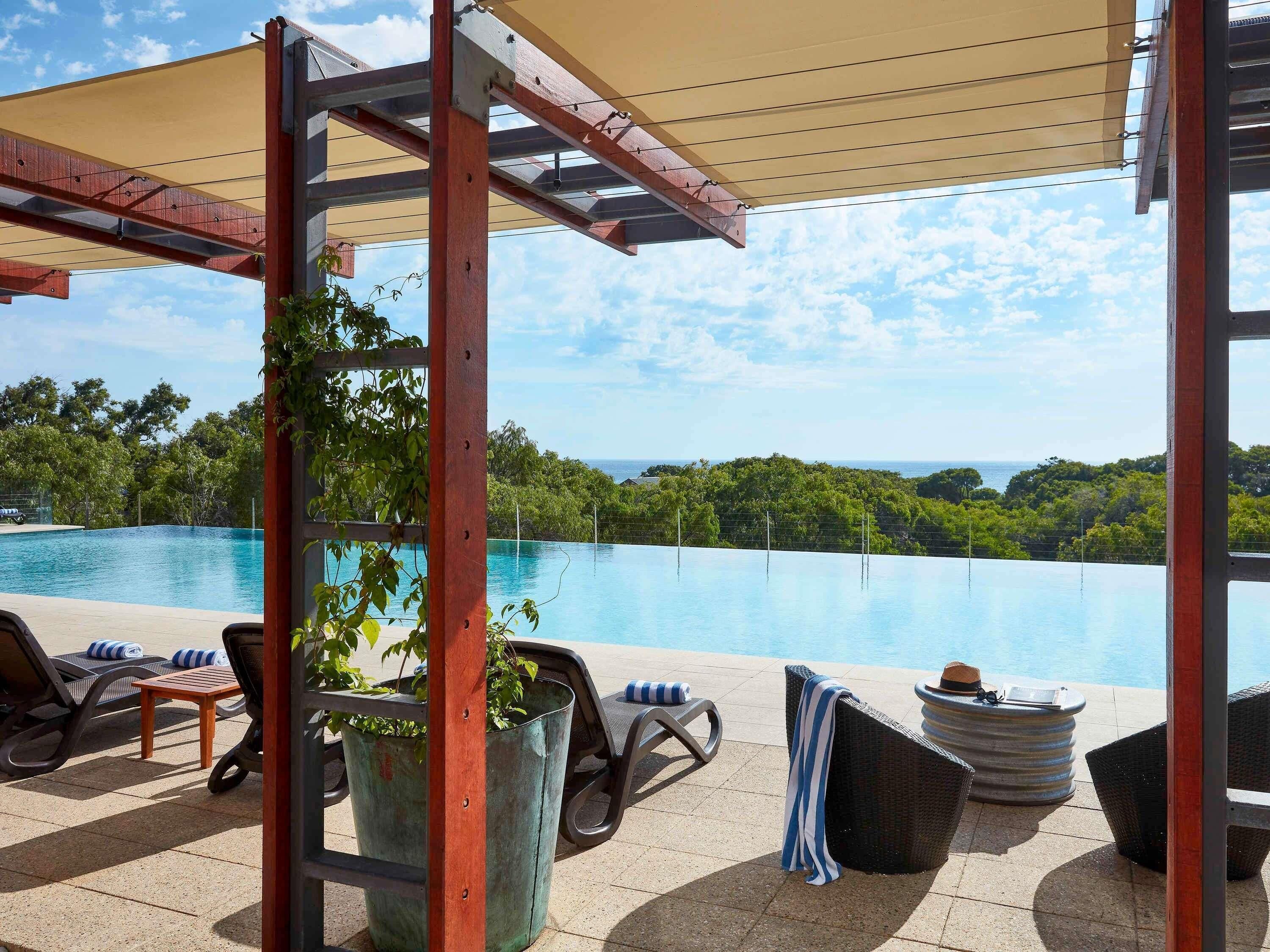 An outdoor pool area with lounge chairs and a pergola.