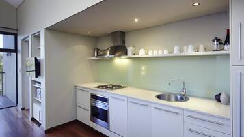 A modern kitchen with white cabinets, stainless steel appliances, and a built-in oven.