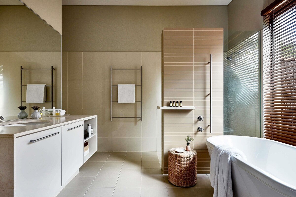 Une salle de bain moderne avec un grand miroir, un meuble-lavabo blanc et une baignoire.