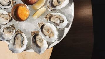 A plate of oysters with lemon wedges and two sauces.