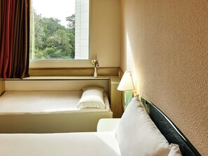 A hotel room with a bed, a nightstand, a lamp, and a window with curtains. - ibis Santo Andre (Santo André)