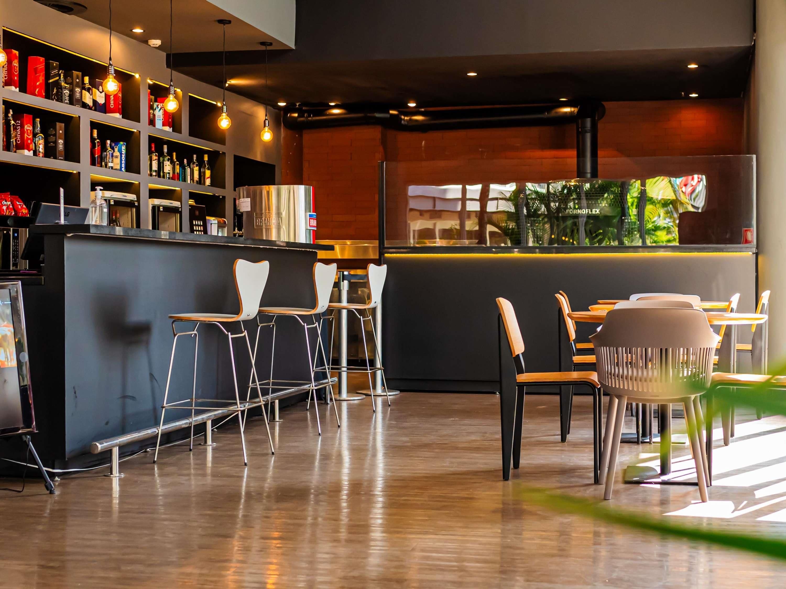 Zona de bar moderna con barra, taburetes y una variedad de botellas.