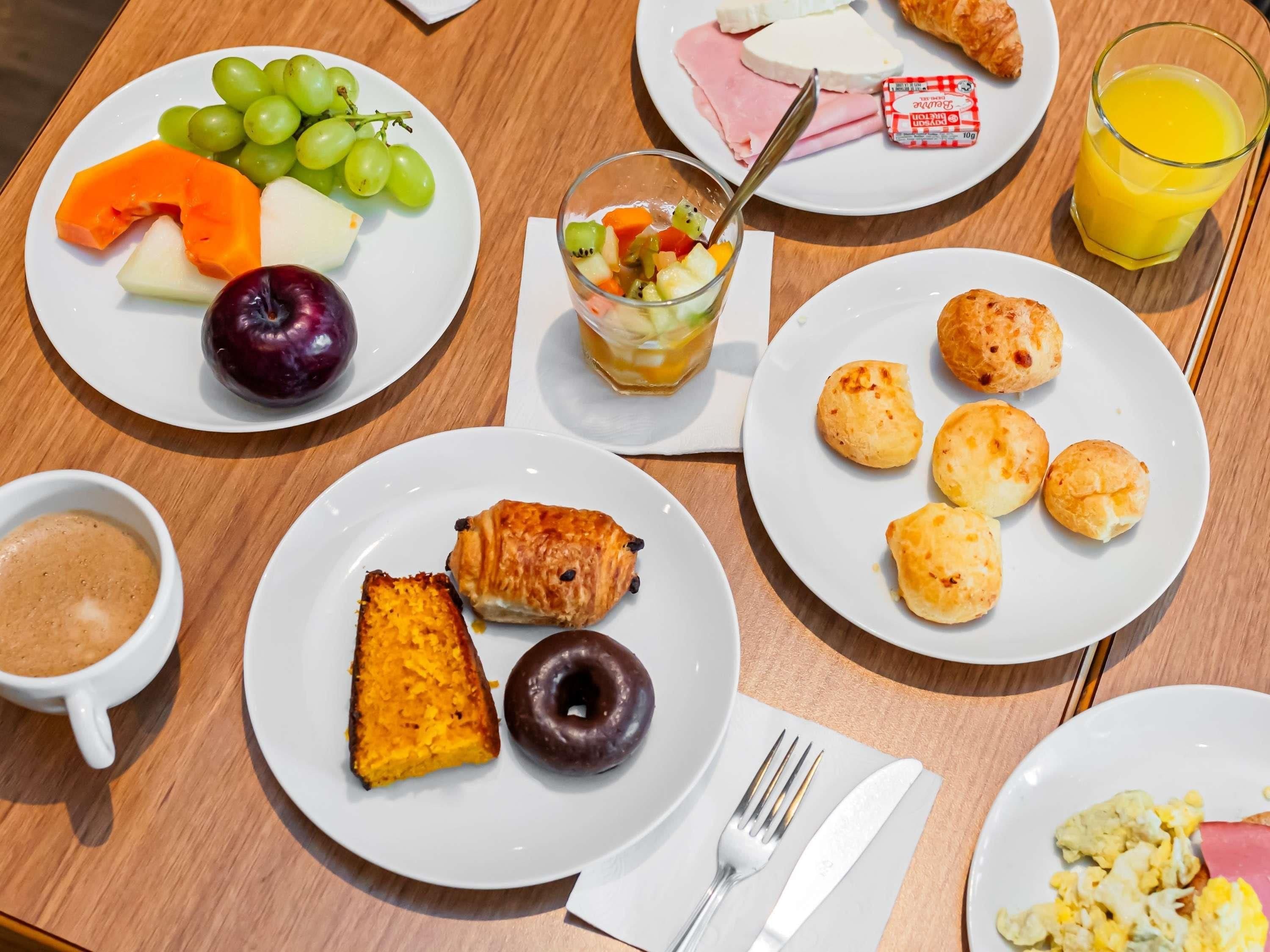 Ett frukostbord med tallrikar fulla av mat, ett glas apelsinjuice och en kopp kaffe.