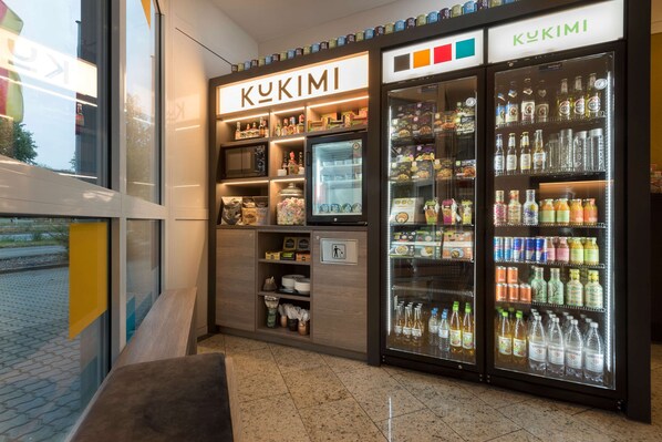 Un petit kiosque où l’on vend des boissons, avec une enseigne indiquant « KUKIMI » et proposant une variété de boissons et d’en-cas.