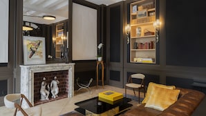 A modern living room with a fireplace, leather sofa, and a bookshelf. - Hôtel Longemalle (Geneva)