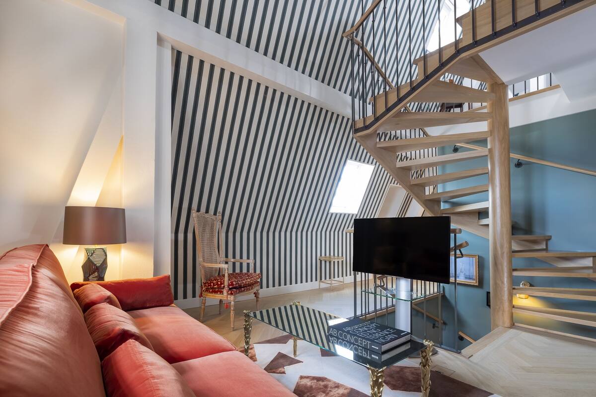 A modern living room with a sofa, a coffee table, a TV, and a staircase.