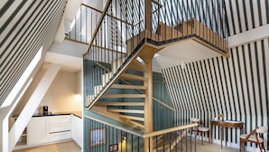 A modern interior with a spiral staircase, a kitchen area, and a dining space. - Hôtel Longemalle (Geneva)