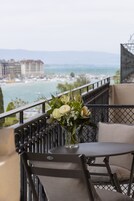 Un balcón con mesa y sillas, un jarrón de flores y vistas al mar y edificios.
