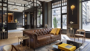 A modern lobby with a leather sofa, a coffee table, and a reception desk. - Hôtel Longemalle (Geneva)