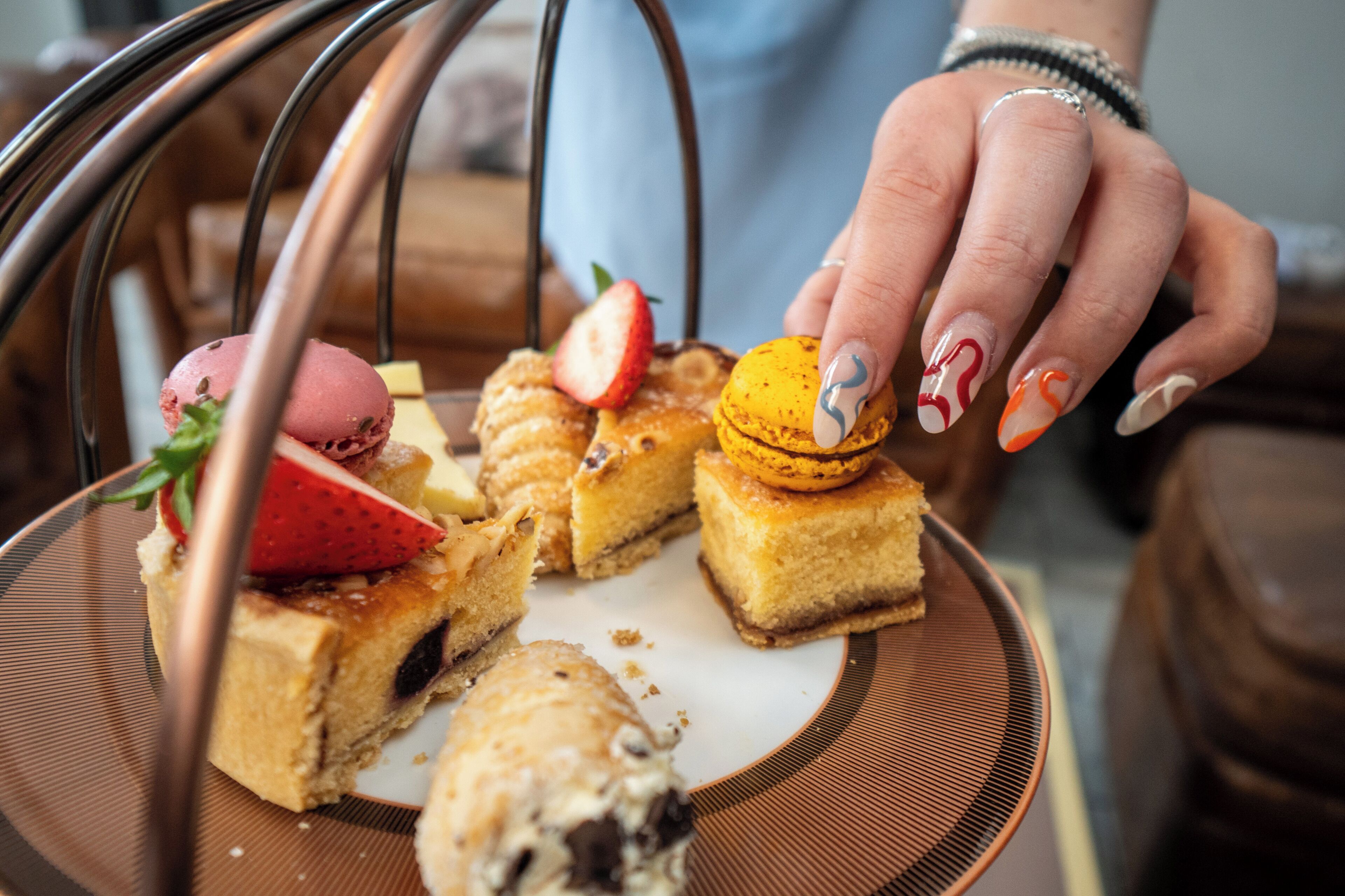 Una bandeja con diversos postres, incluyendo macarons, un pastel con fresa y una bola de helado.