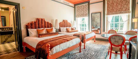 A hotel room with two beds, a dining area, and large windows.