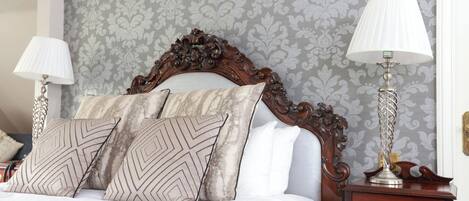 A neatly made bed with patterned pillows, a wooden headboard, and two bedside lamps.