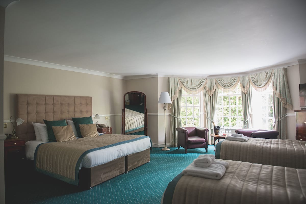 A hotel room with a large bed, a smaller bed, a chair, and a desk.