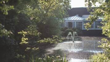 A conservatory with a fountain, surrounded by lush greenery.