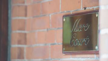 A metal plaque with the inscription "Mere Court" mounted on a brick wall.