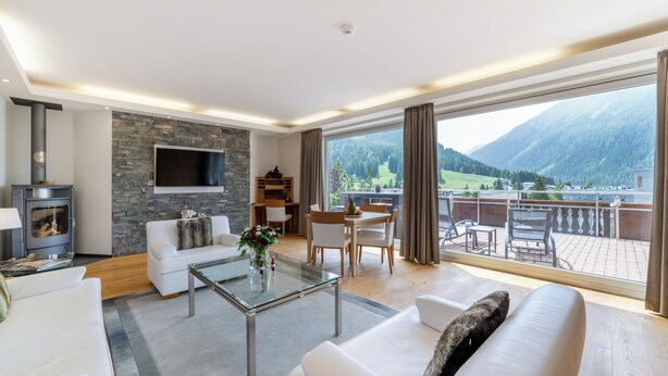 Een moderne woonkamer met een open haard, een flatscreen-televisie en een eethoek met uitzicht op bergen.