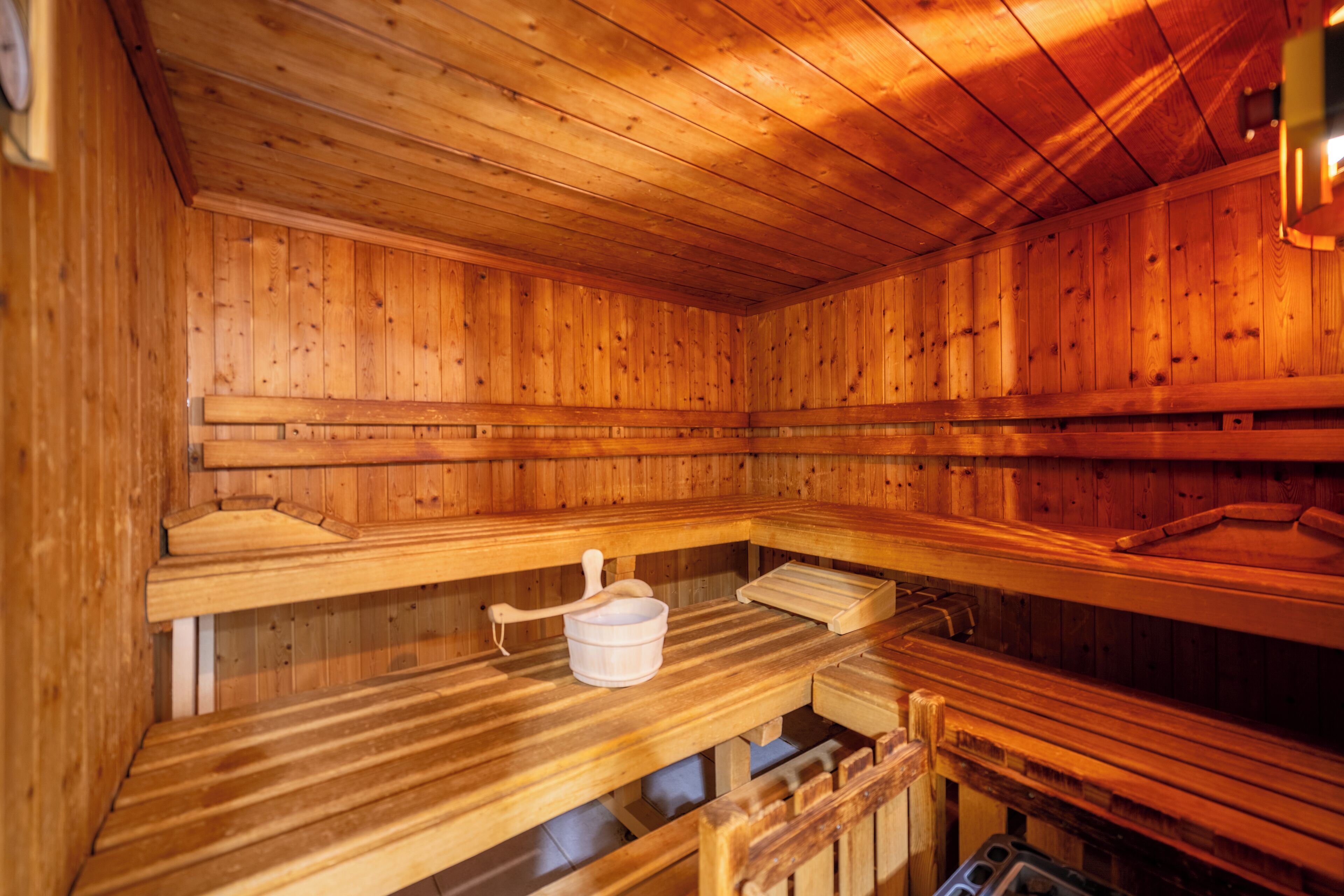 Eine Holzsauna mit Bänken und einem Eimer.