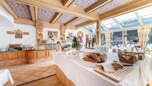 Een ontbijtbuffet met diverse broden en gebak, houten kasten en een plafond met bloemen.