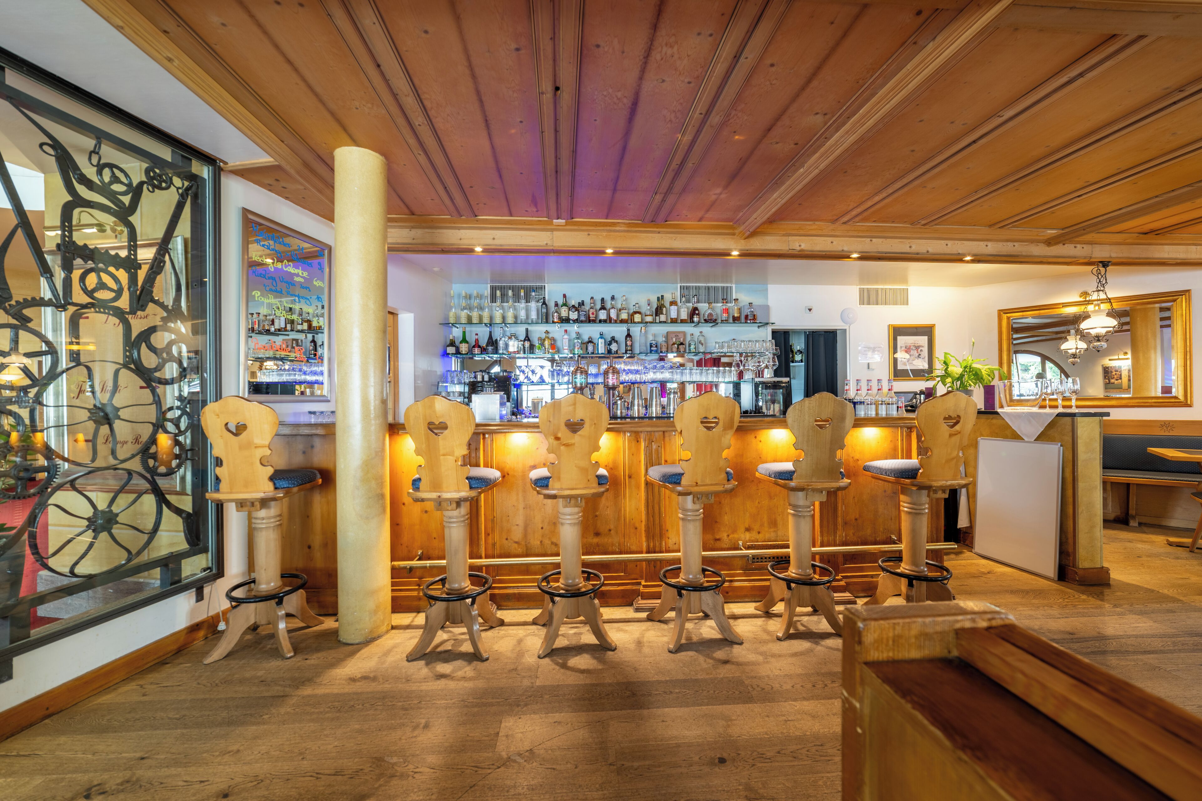 A bar area with wooden bar stools and a well-stocked bar.