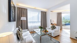 Een moderne woonkamer met een glazen salontafel, twee witte banken, een lamp en uitzicht op de omgeving.