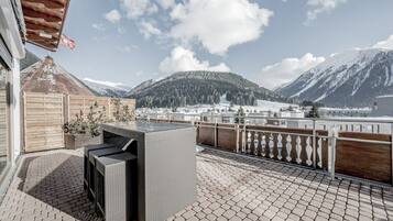 A patio with wicker furniture, a wooden fence, and a view of snow-covered mountains.