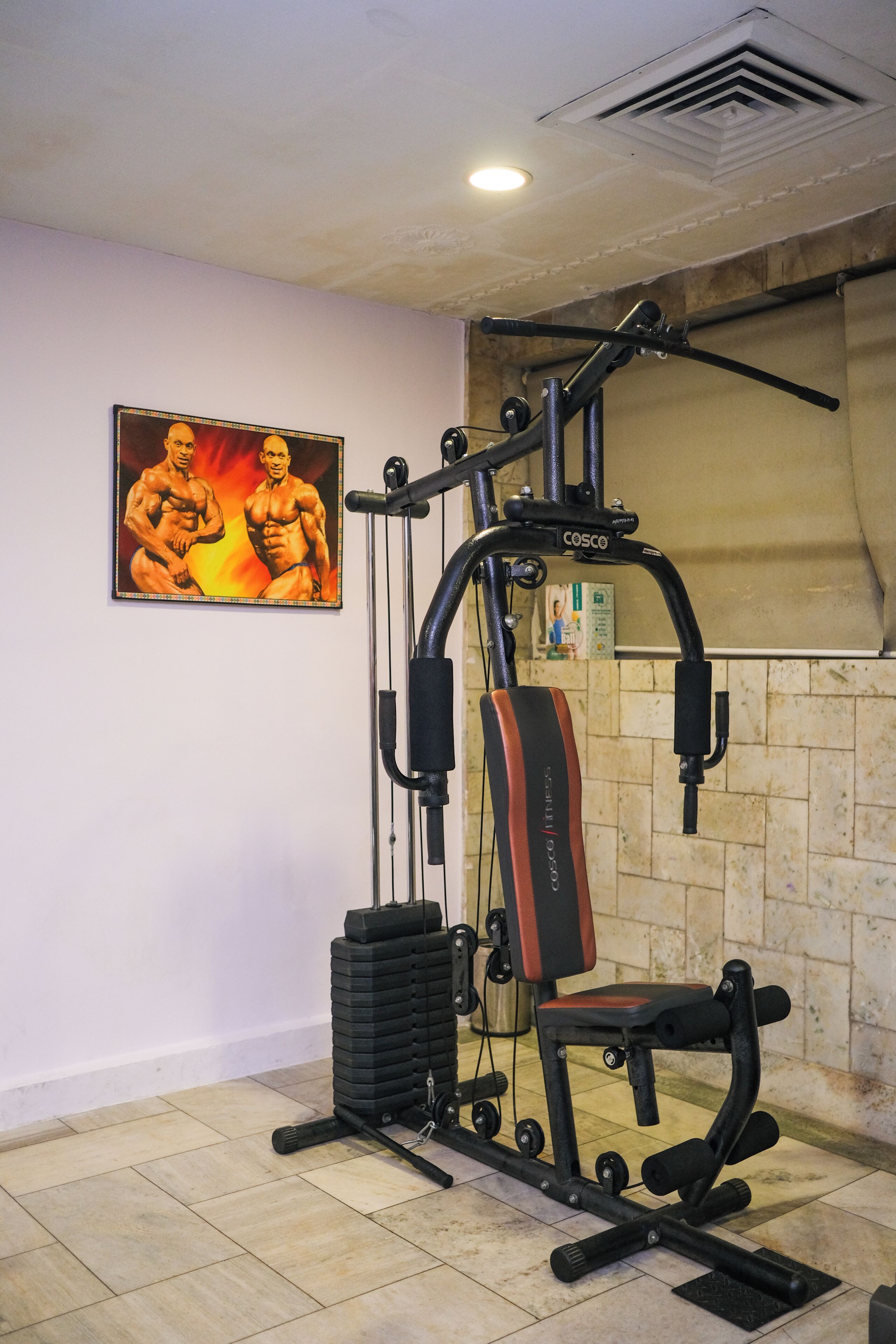 Un gimnasio con una torre de pesas, un banco y un espejo adosado a la pared.