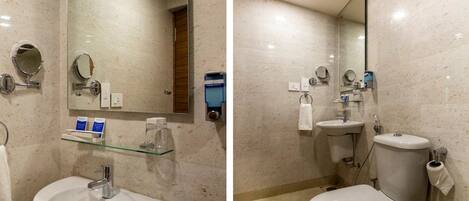 A bathroom with a sink, mirror, toilet, and glass shelf.