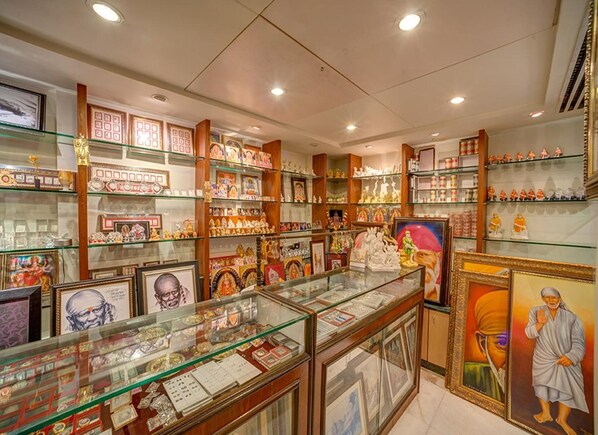 A well-lit store with glass display cases and shelves filled with various items. - Renest Shraddha Inn - Shirdi (Rahata)