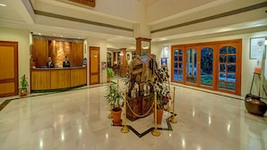 Un hall d’entrée spacieux, doté d’un comptoir de réception, d’une grande pièce maîtresse décorative et offrant une vue sur l’extérieur grâce à de larges fenêtres.