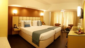 A hotel room with a large bed, a desk, a chair, and a coffee machine. - Hotel Sagar Plaza (Pune)