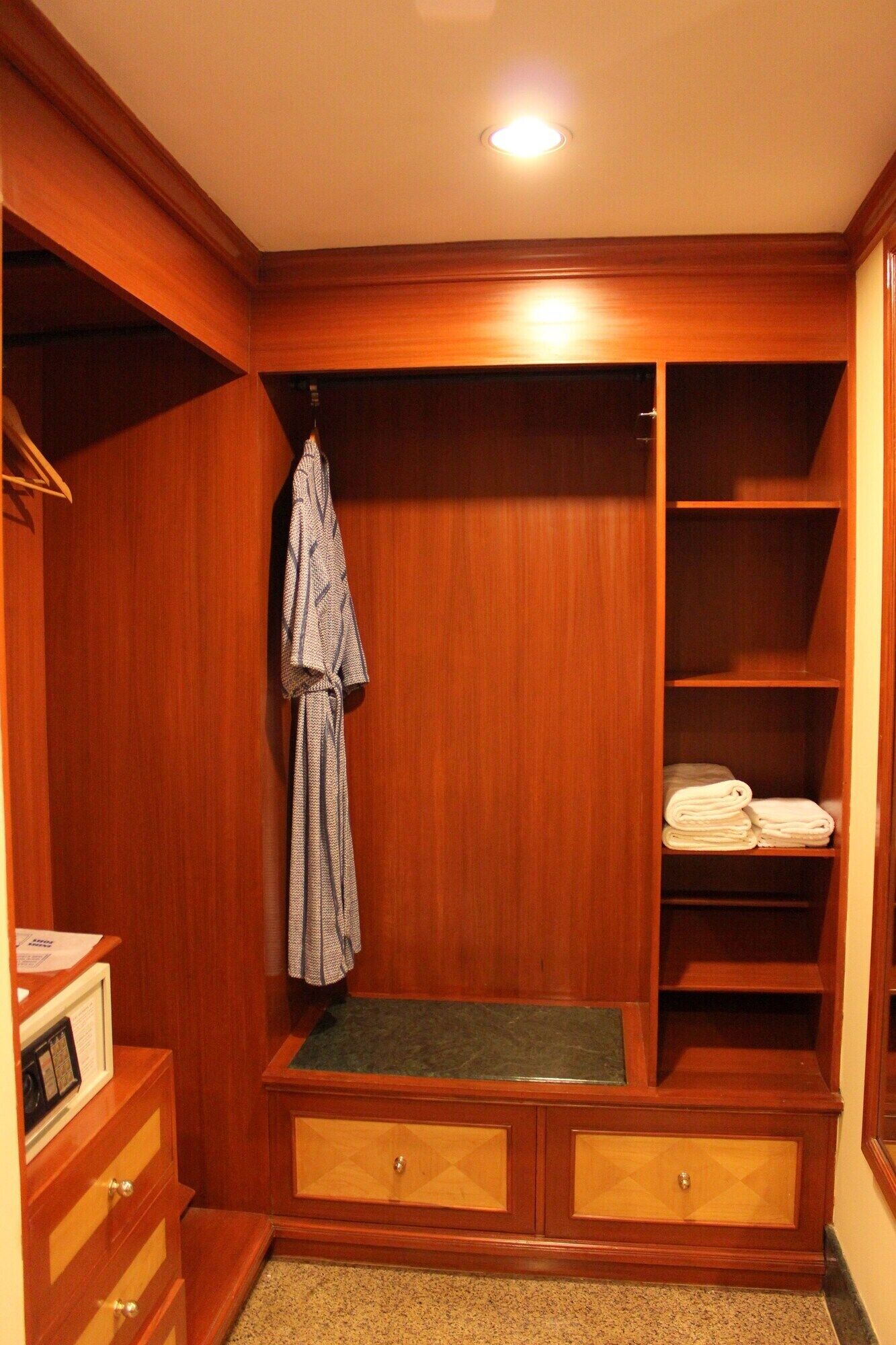 A wooden walk-in closet with shelves, a hanging rack, and a bench.