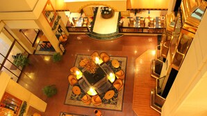 A spacious lobby with a central seating area, a reception desk, and a staircase. - Hotel Sagar Plaza (Pune)