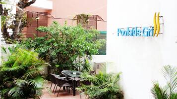 Un patio al aire libre con una mesa y sillas, rodeado de plantas en macetas y una valla.