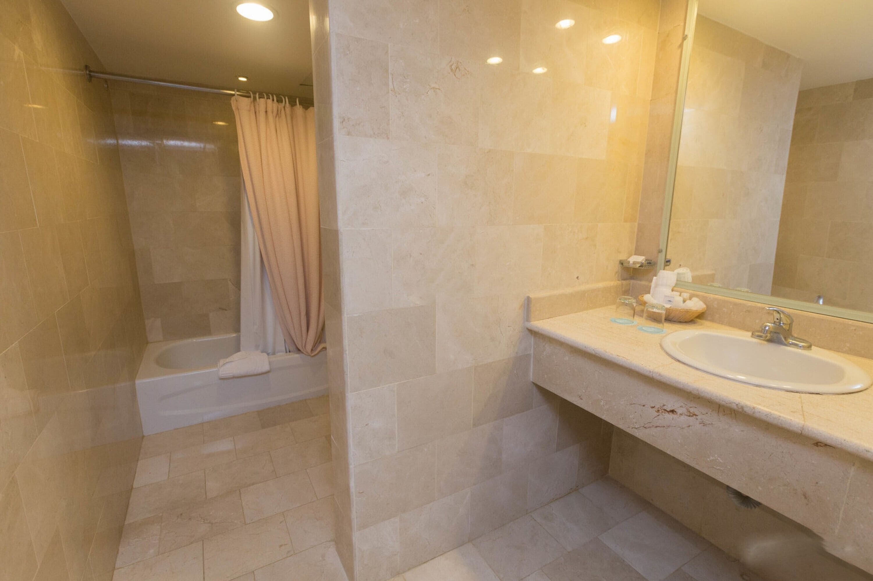 Un baño moderno con una bañera, un lavamanos y un espejo grande.