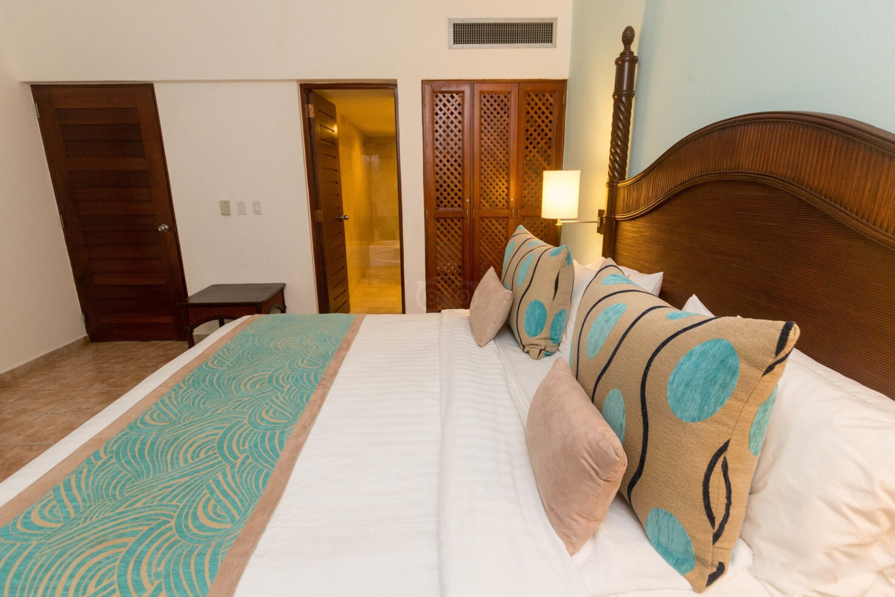 A hotel room with a bed, a wooden headboard, a nightstand, a lamp, and a wardrobe.