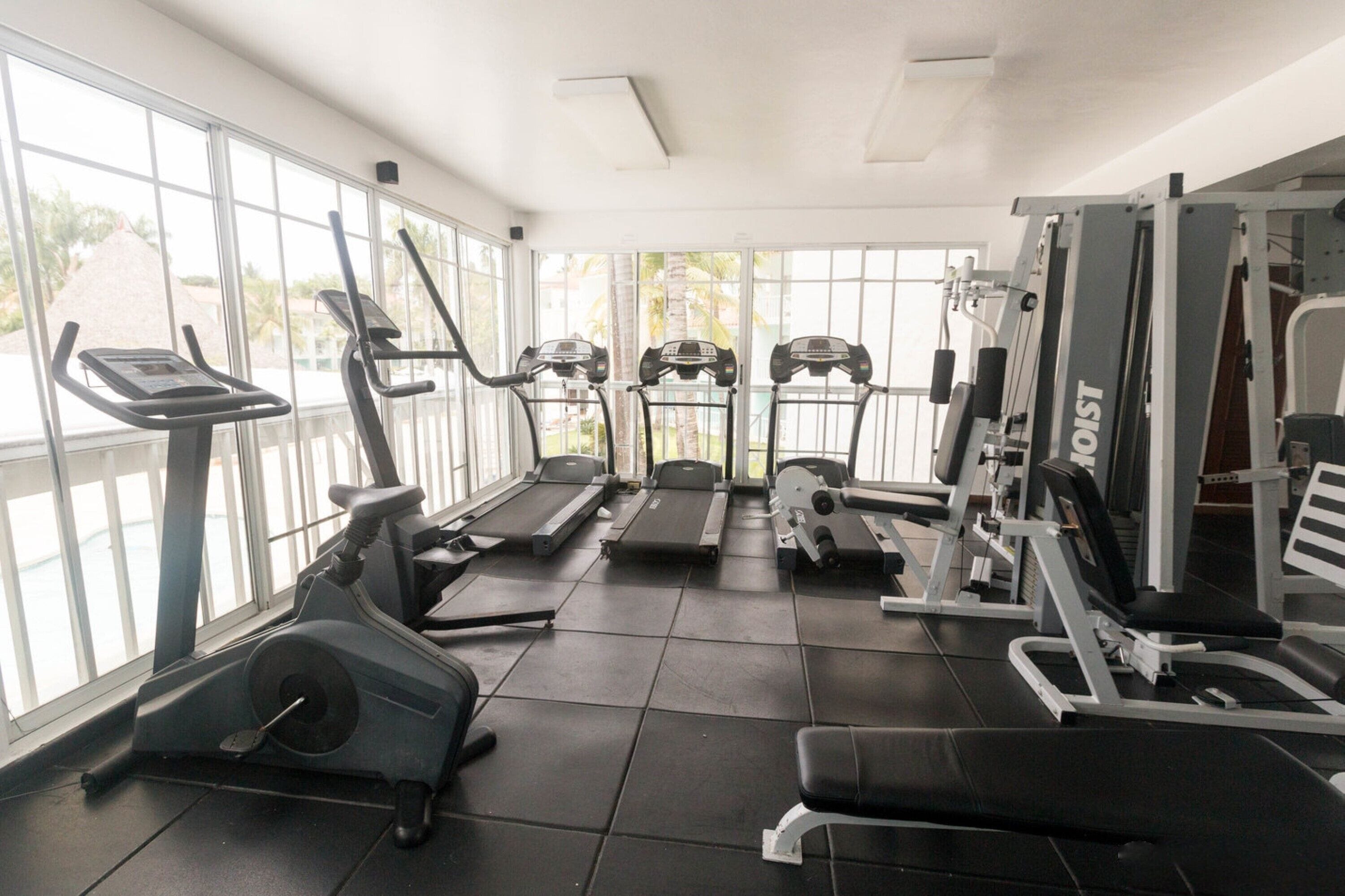 Un gimnasio con cintas de correr, elípticas y equipo de pesas.