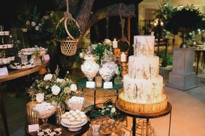 A multi-tiered wedding cake with floral decorations, surrounded by various dessert options and floral arrangements.