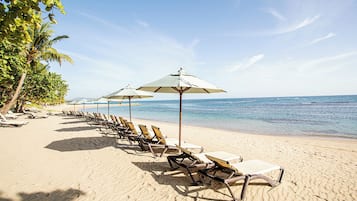 Trên bãi biển, cát trắng, ghế dài tắm nắng, dù trên bãi biển