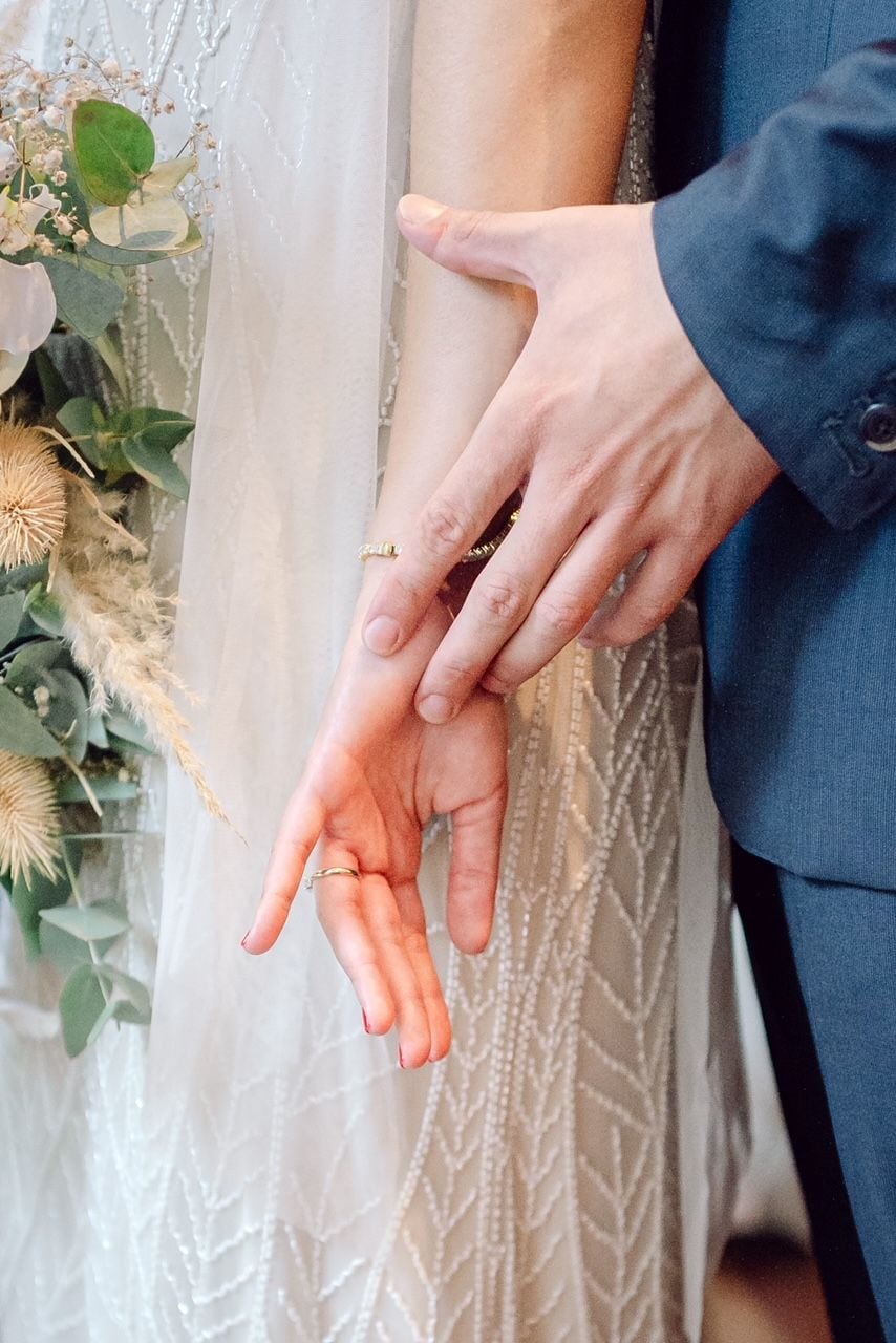 A close-up of hands, one wearing a ring and the other a ring.