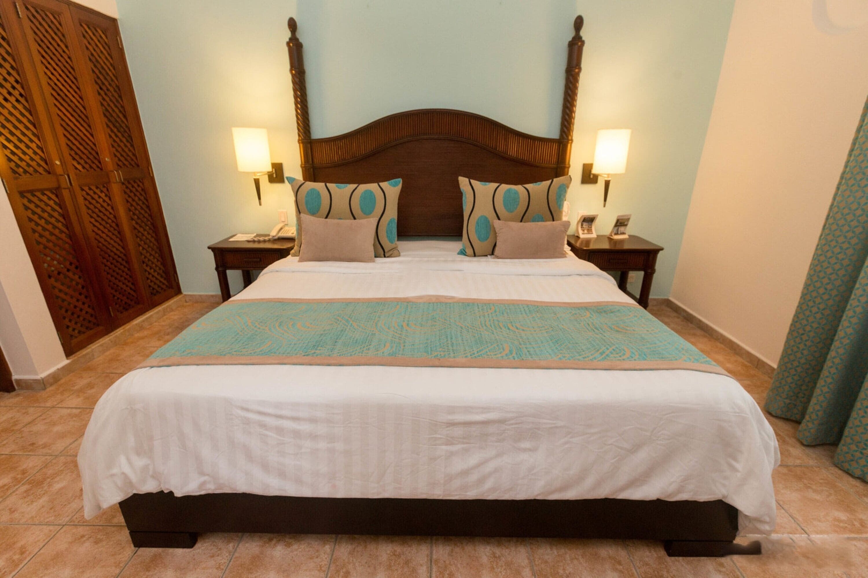 A large bed with a wooden headboard, two bedside tables with lamps, and a patterned bedspread.