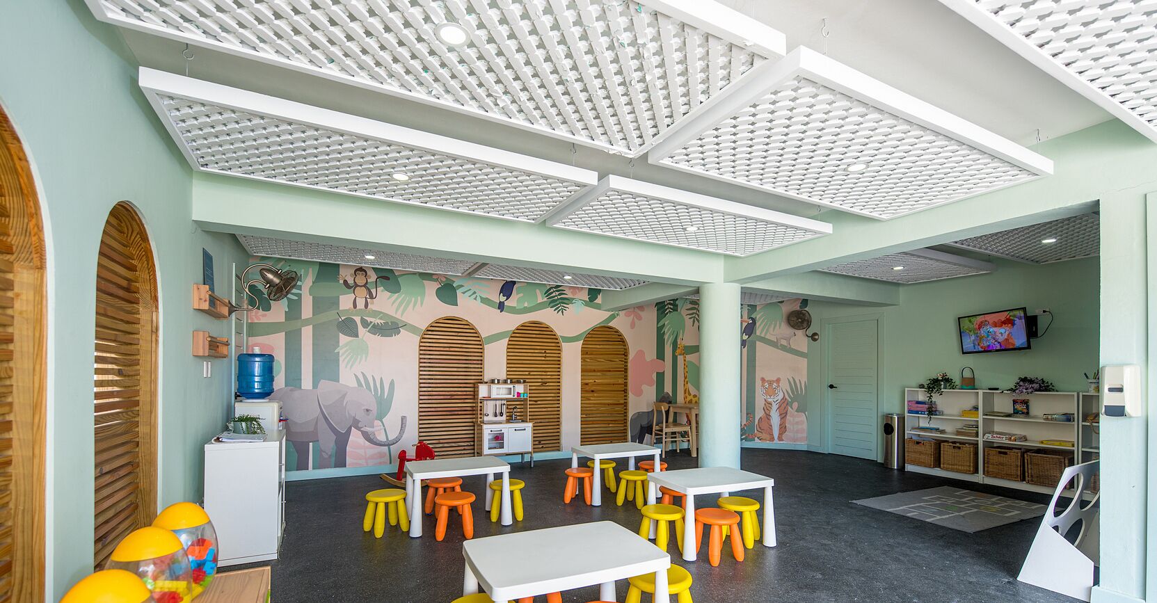 A children's play area with tables and stools, a water dispenser, and educational toys.