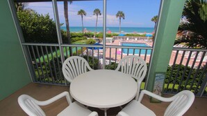 A balcony with a view of the beach, a pool, and palm trees. - Silver Sands Gulf Beach Resort by RVA (Longboat Key)