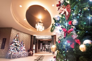 A hotel lobby with a Christmas tree and a large circular light fixture.