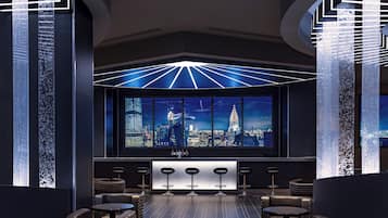 Zona de bar moderna con vistas a la ciudad, taburetes y un diseño de techo original.