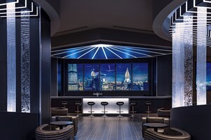 Zona de bar moderna con vistas a la ciudad, taburetes y un diseño de techo original.